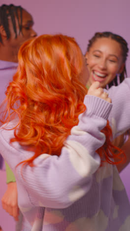 Vertical-Video-Studio-Shot-Of-Gen-Z-Friends-Dancing-And-Posing-For-Selfie-At-Party-Against-Pink-Background